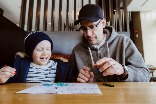 Father and son colouring in restaurant booth waiting for food