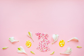 Easter funny bunny from topping. Decorative eggs with flower petals. Flat lay on a pink background
