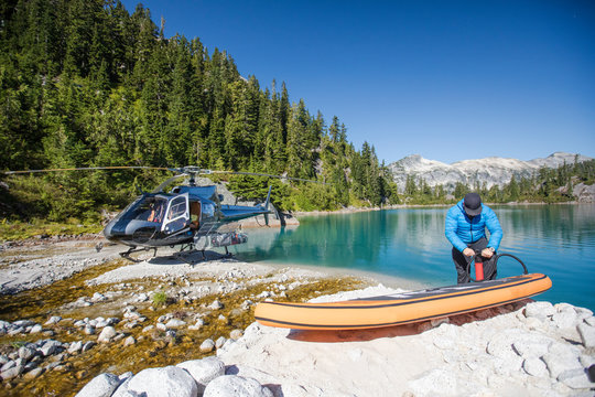 Adventurous man pumps up inflatable SUP next to a remote lake.