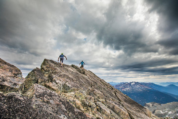 Two climbers approach the summit of a mountain peak.