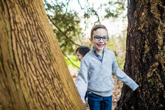 Young boy wearing glasses playing in the forest.