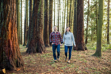 attractive trendy couple walking through forest, looking ahead.