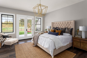 Master bedroom interior in new luxury home. French doors lead outside