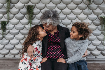 Portrait of grandmother sitting close with twin grandchildren
