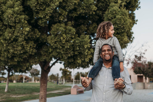 Joyful son sitting on a happy father's shoulders at park playground - Powered by Adobe