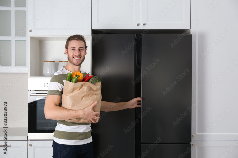 Wall mural Man with fresh products near modern refrigerator in kitchen