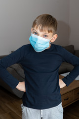 Sad boy in coronavirus quarantine at home in blue medical mask. COVID19 epidemic control of...