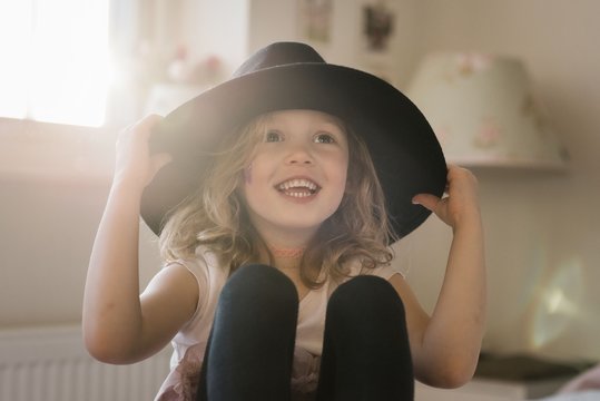 portrait of a young girl laughing at home playing dress up