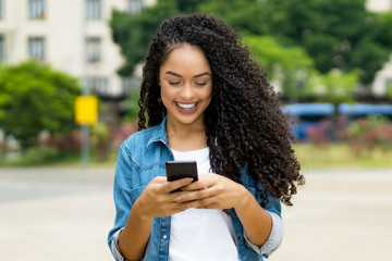 Brazilian young adult woman with retainer sending message with mobile phone