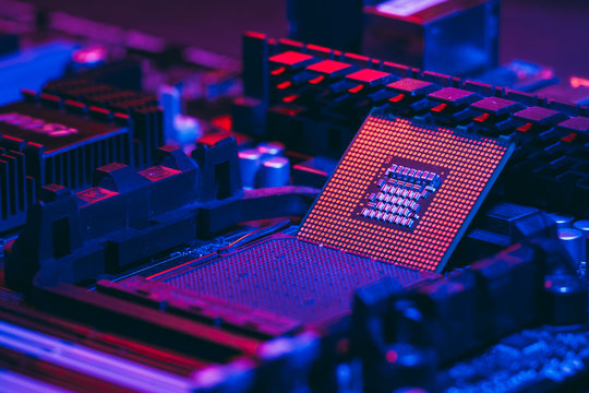 The processor on the motherboard in neon light. Computer parts. Close-up photo.