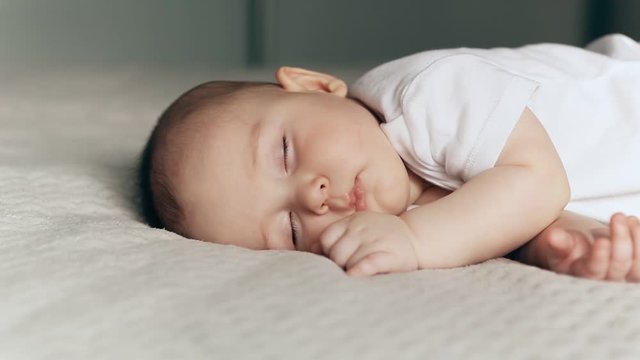 Sleeping cute baby boy on gray blanket