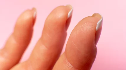 three fingers inside on a female hand, close-up. pink background.