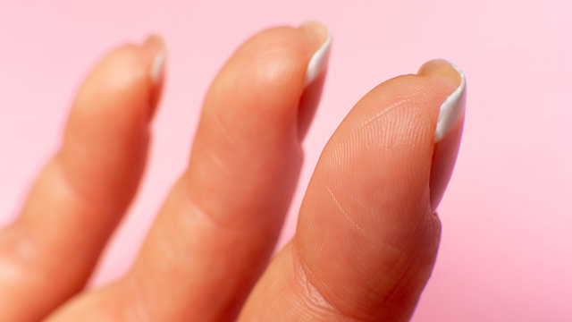 three fingers inside on a female hand, close-up. pink background.
