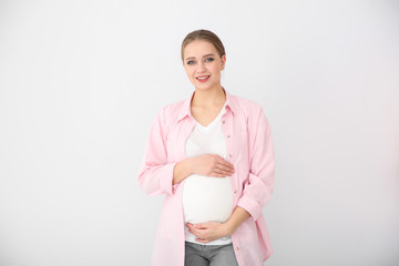 Happy young pregnant woman on white background