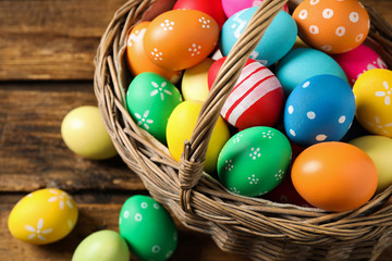Fototapeta na wymiar Colorful Easter eggs in basket on wooden background, closeup