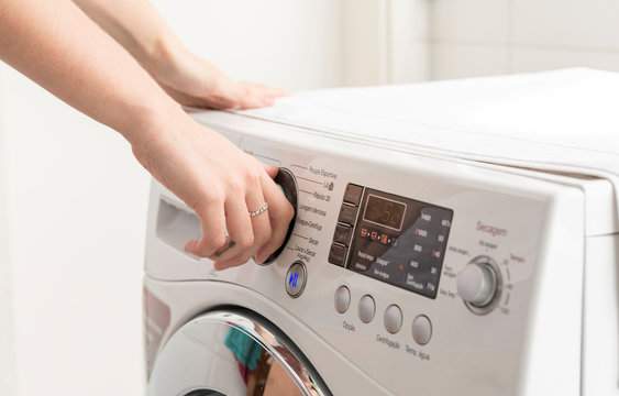 Woman hand operating a washing machine at home