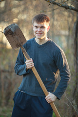 Agronomist handsome strong man with shovel on  background of flower beds