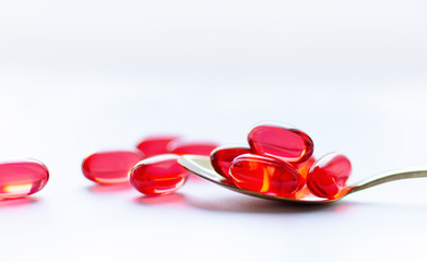 Red capsules in a golden spoon on white background. Traditional medicine treatment.