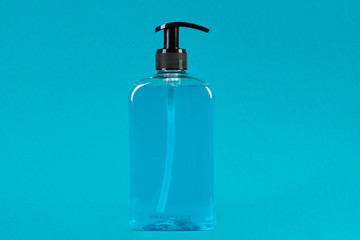 Liquid soap dispenser on blue background with copy space