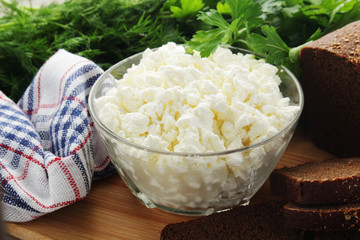 A bowl with cottage cheese, a bunch of green and rye bread