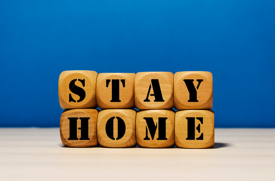 Naklejki Stay Home on wood cube with blue background