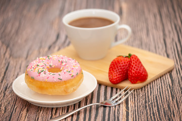 Dessert, Donuts, chocolate and strawberry circles, sugar and cream on Donuts and hot coffee cups, preparation for a break or party on the wooden table background.