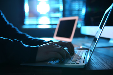 Hacker with laptop in dark room, closeup. Cyber crime