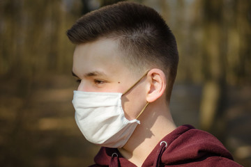 Close up portrait of a young man in a disposable medical mask. The guy in the medical mask. Pandemic Coronavirus Covid 19. Quarantine. Europe.