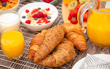 Breakfast Served in the morning with Fruit Yogurt, Butter croissant and corn flakes Whole grains and raisins with milk in cups and Strawberry, Raspberry, Kiwi, Fresh Orange Juice on breakfast table