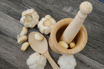 garlic grains on wooden background, close up, wood garlic crusher and garlic,