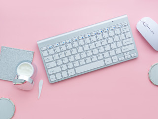 keyboard and mouse near a face cream container on pink