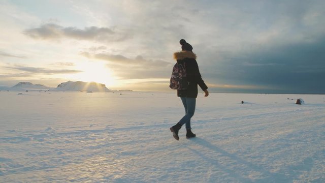 Yong beautiful woman traveler walking on snow desert in Iceland. Slow motion shot at sunset or sunrise. Around Solheimasandur dc3 Plane crash area 