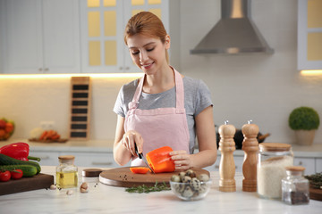 Young woman cooking at table in kitchen