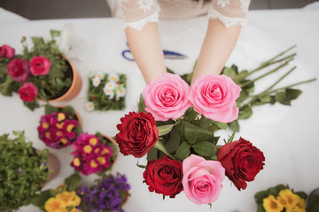 Woman Preparing to trim red and pink roses and beautiful flower arrangements in the home, flower arrangements with vase for gift-giving for Valentine's Day and Business in the family on the on table