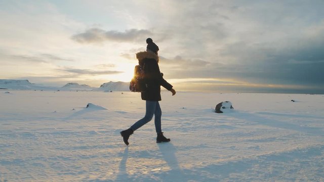 Yong beautiful woman traveler walking on snow desert in Iceland. Slow motion shot at sunset or sunrise. Around Solheimasandur dc3 Plane crash area 