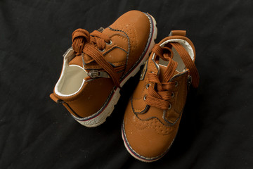 pair of orange shoes for kid on black background