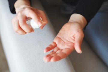 woman disinfecting hands with hand disinfectant spray in a bottle due to corona virus infection risk