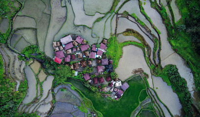 Aerial view on tiny community houses settlement surrounded by rice paddy fields in the mountains....