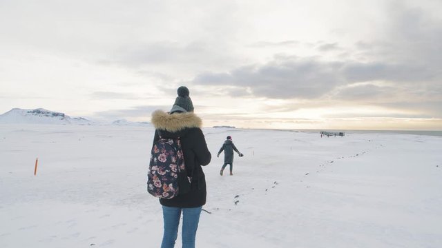 young woman photographer takes pictures of her friend at sunrise in Solheimasandur dc3 Plane Crash in Iceland