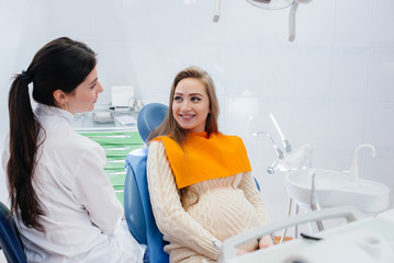 Fototapeta premium A professional dentist treats and examines the oral cavity of a pregnant girl in a modern dental office. Dentistry