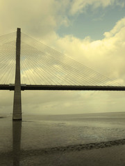 Part of the Vasco de Gama Lisbon bridge that crosses the river Tejo reflected in the water on a cloudy day.