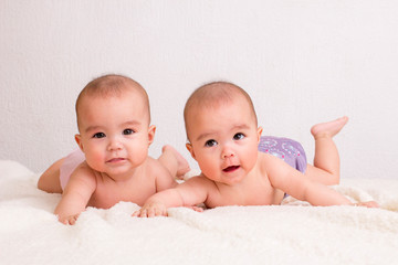 Baby twins girls with cloth diaper on a bed