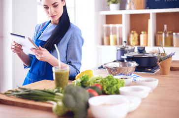 Young woman using a tablet computer to cook in her kitchen