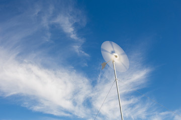 Close up wide angle view of a spinning wind turbine charging batteries in an off the grid electricity installation on a farm in the Karoo in the Western Cape of South Africa