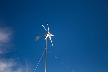 Close up wide angle view of a spinning wind turbine charging batteries in an off the grid electricity installation on a farm in the Karoo in the Western Cape of South Africa