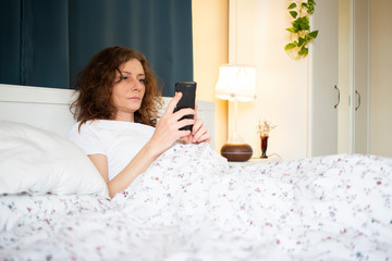 Obraz na płótnie Canvas woman using smartphone in bed
