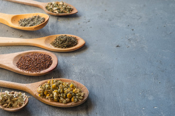 herbs with wooden spoon in gray slate background