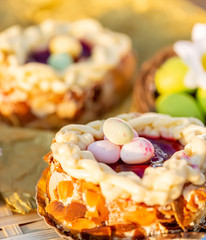 Easter cake on a wooden table and bronze paper. Nuts and oval sweet sweets in the form of eggs. Toned image. Closeup. 