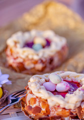 Easter sponge cake nest. Nuts and oval sweet sweets in the form of eggs. Blurred background. Shallow depth of field. Toned image.