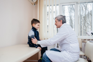 Obraz premium A young boy is listened to and treated by an experienced doctor in a modern clinic. A virus, and an epidemic